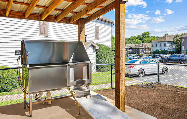 A stainless steel oven is on a stand in front of a house.