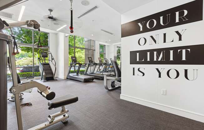 a gym with cardio equipment and a large sign that says your only limit is you