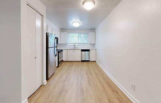 A kitchen with a refrigerator, sink, and trash can.