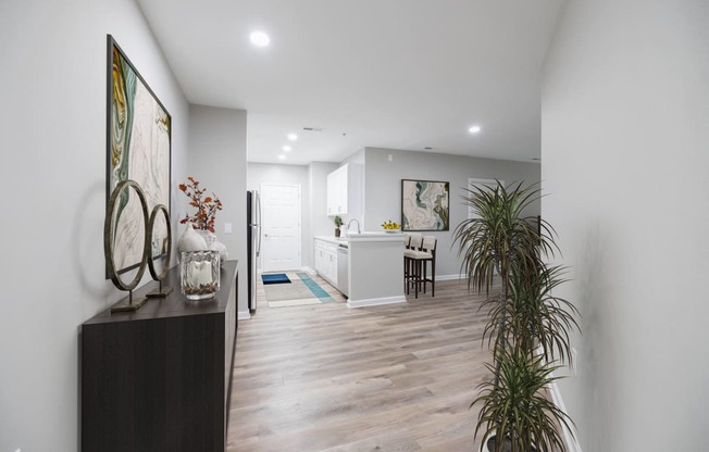 a living room and kitchen with white walls and a wooden floor