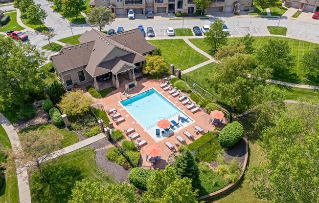 An aerial view of a house with a pool and a parking lot.