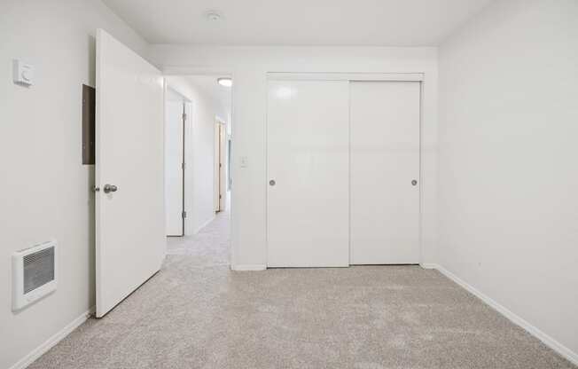 A long hallway with white doors and carpeted floors.