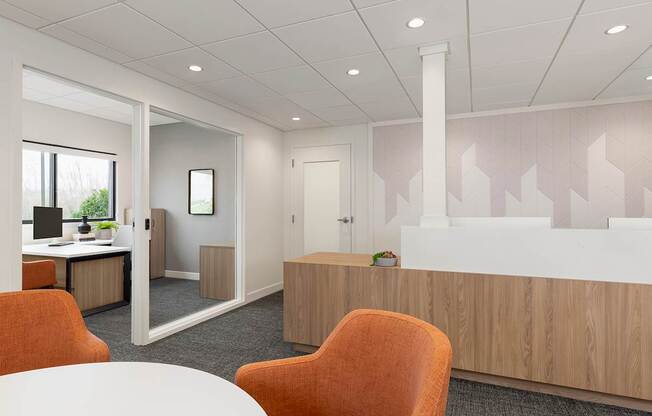 A white table is in the middle of a room with orange chairs.