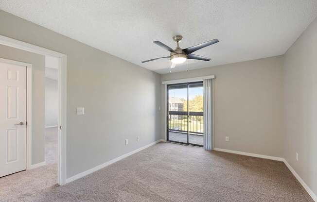 Model room with sliding door to private patio, carpet, and ceiling fan at Fountains at Lee Vista in Orlando, Florida.