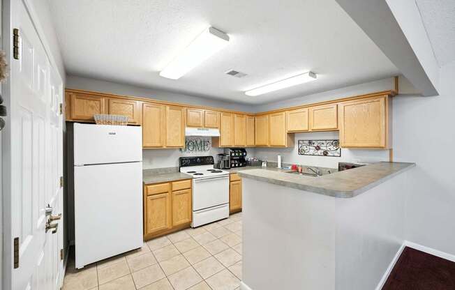 A kitchen with white appliances and wooden cabinets at Arbors at Georgetown Apartments, Lansing, MI
