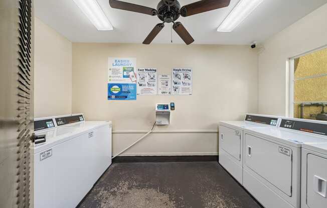 a washer and dryer room with a ceiling fan at The Village Apartments, California