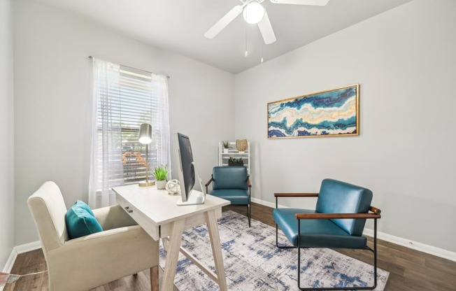 a living room with chairs and a table and a ceiling fan