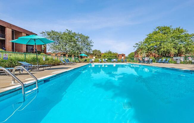 a large blue swimming pool with chairs and umbrellas