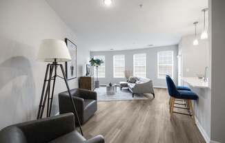 A well-lit living room with a grey sofa, a black chair, and a wooden floor at Harbor Pointe Apartments, Bayonne