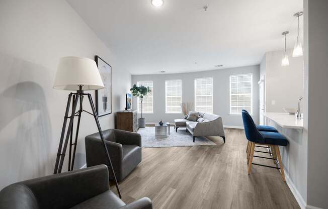 A well-lit living room with a grey sofa, a black chair, and a wooden floor at Harbor Pointe Apartments, Bayonne