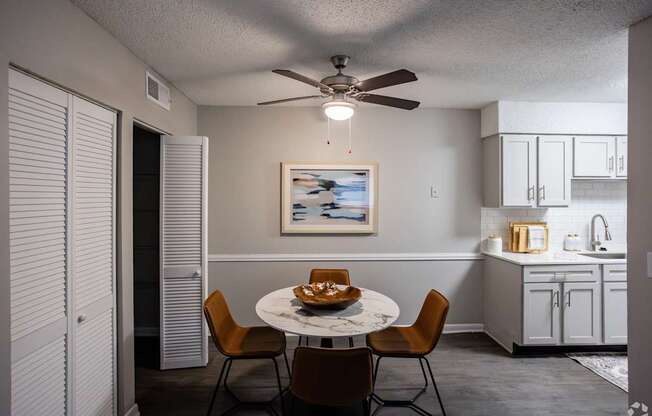 A dining room with a table set for two and a ceiling fan.