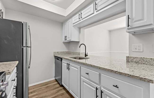 A kitchen with white cabinets and a granite countertop.