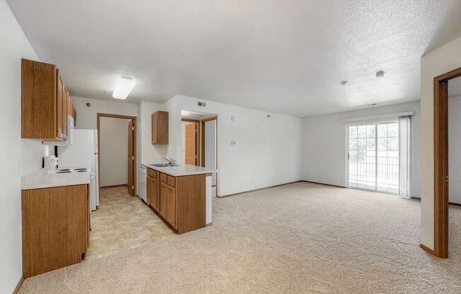 an empty living room and kitchen with white walls and wood cabinets