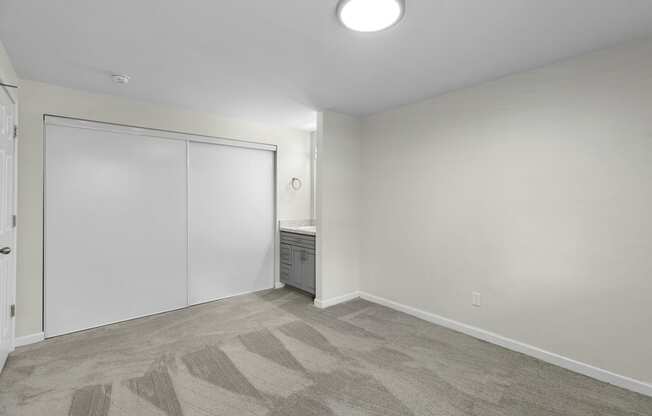 a bedroom with white walls and carpet at Swiss Gables Apartment Homes, WA 98032