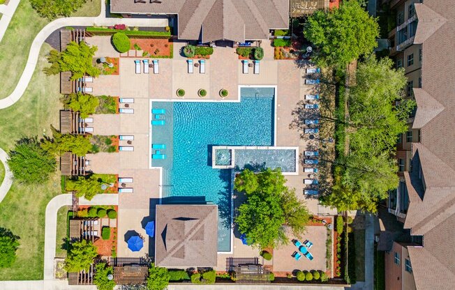 arial view of a swimming pool in the middle of a house with trees