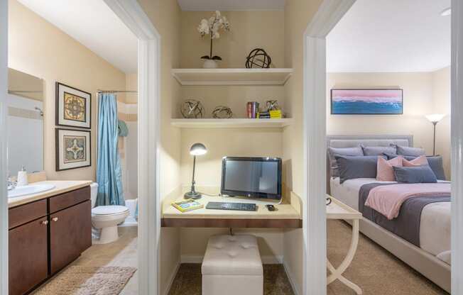 a bedroom with a bed and a desk with a computer   and a bathroom