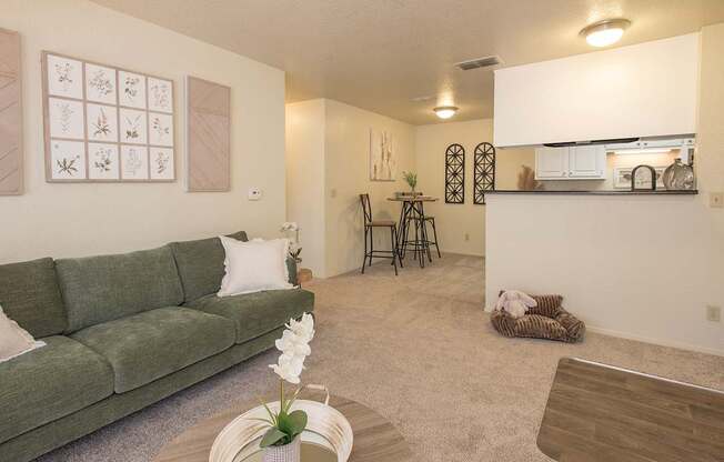 A living room with a green couch and a coffee table with a vase of flowers on it at Zinfandel Village Apartments, California, 95670