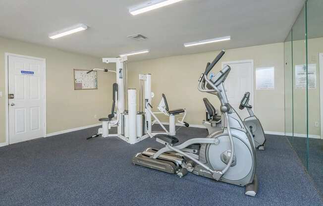 A gym with a treadmill, elliptical trainer and a stationary bike.