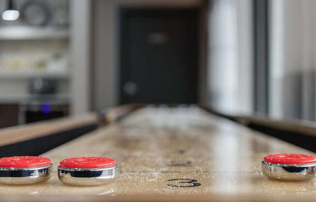 A table with two red buttons on it and a blurry background.