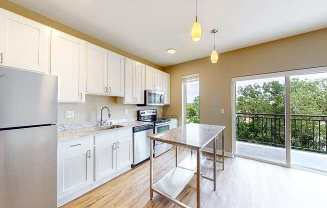 a kitchen with white cabinets and stainless steel appliances and a balcony