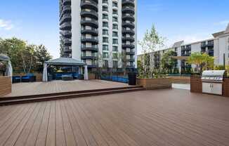 A wooden deck with a gazebo and a tall building in the background.