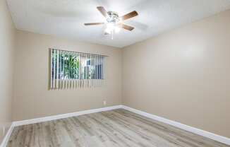 an empty living room with a ceiling fan and a window