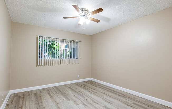 an empty living room with a ceiling fan and a window