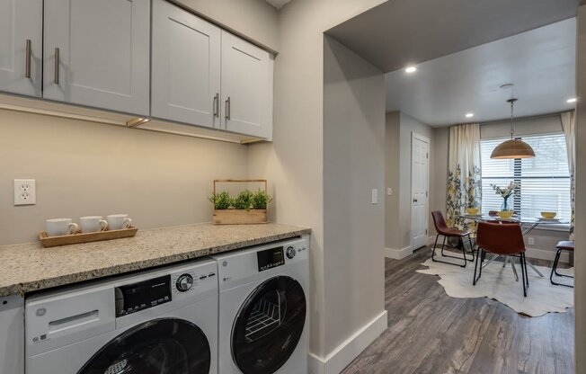 a washer and dryer in a laundry room with a table and chairs