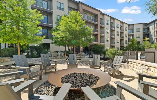 A large circular fire pit sits in the middle of a patio surrounded by chairs.