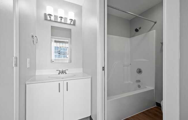 A white bathroom with a glass shower stall and a window.