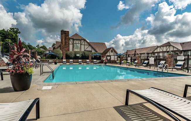 A pool area with a large swimming pool, lounge chairs, and a potted plant