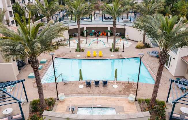 A pool surrounded by palm trees and a hot tub.
