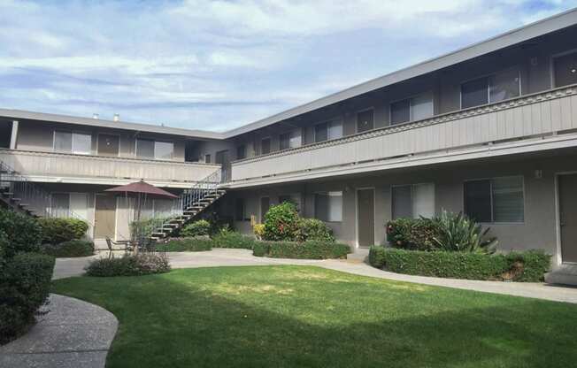 the courtyard of an apartment building with a lawn and a staircase