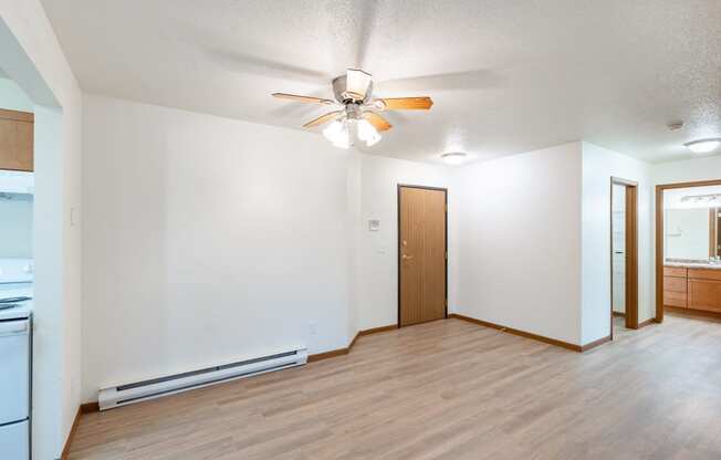 an empty living room with a ceiling fan and a kitchen. Fargo, ND Flagstone Apartments