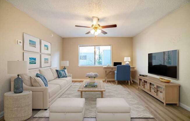 A living room with a white couch, a coffee table, and a flat screen TV.
