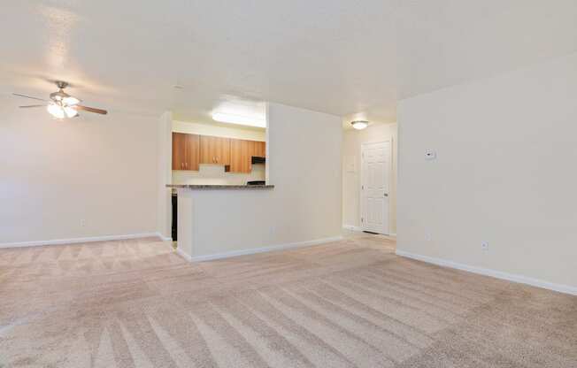 an empty living room and kitchen with a ceiling fan