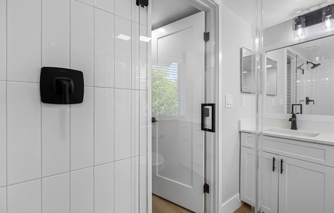 A white bathroom with a black soap dispenser on the wall.