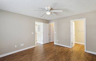 A room with a ceiling fan and wooden floors.
