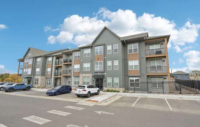 an apartment building with cars parked in a parking lot