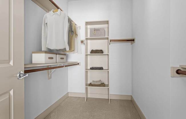 A white closet with a shelf and a white door.