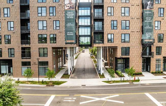 A street view of a residential area with apartment buildings on both sides and a pedestrian crossing in the foreground.