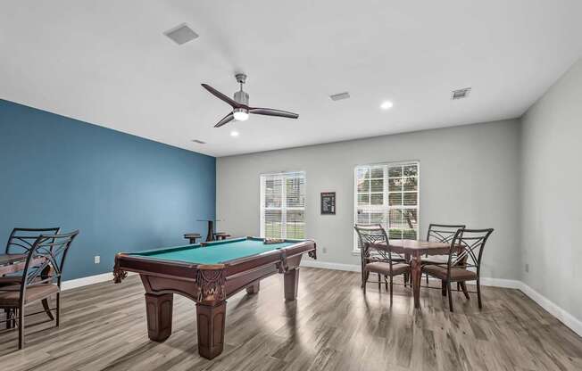 A pool table is in the middle of a room with a ceiling fan.