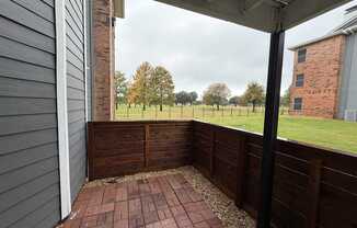 A patio with a brick floor and a wooden fence.