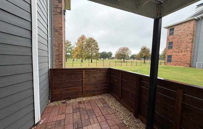 A patio with a brick floor and a wooden fence.