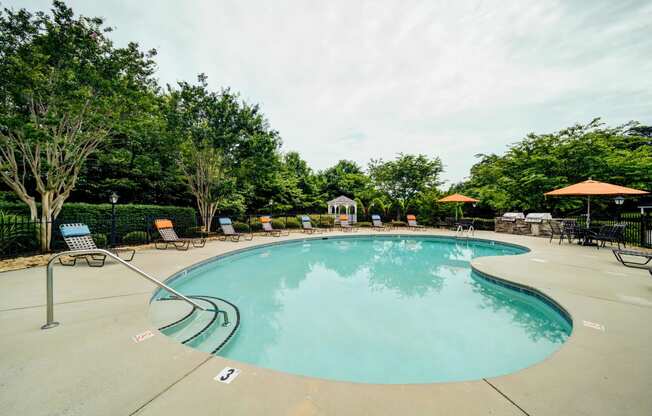 Resort Style Kidney Shaped Pool with Lounge Chairs and Tables with Umbrellas Around