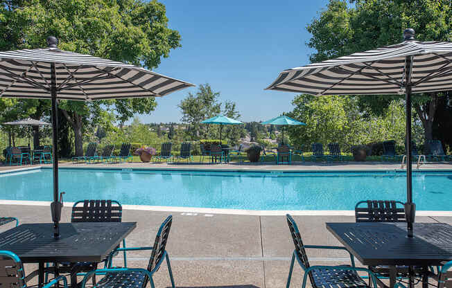A pool with a table and chairs with umbrellas at Sunset Summit, Rocklin, CA, 95765