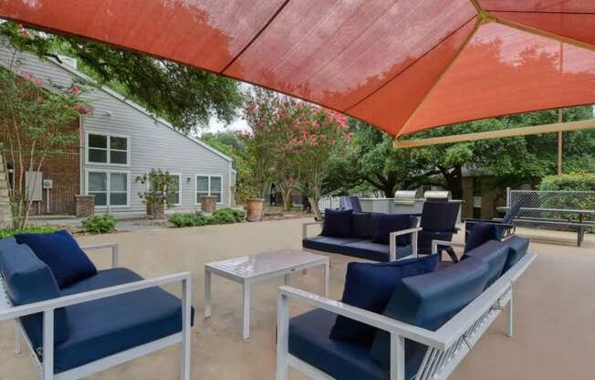 A patio with blue chairs and a red umbrella.