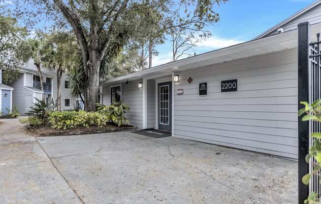 a white house with a driveway and a tree in front of it