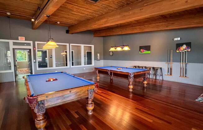 A pool table in a room with wooden floors and a ceiling.