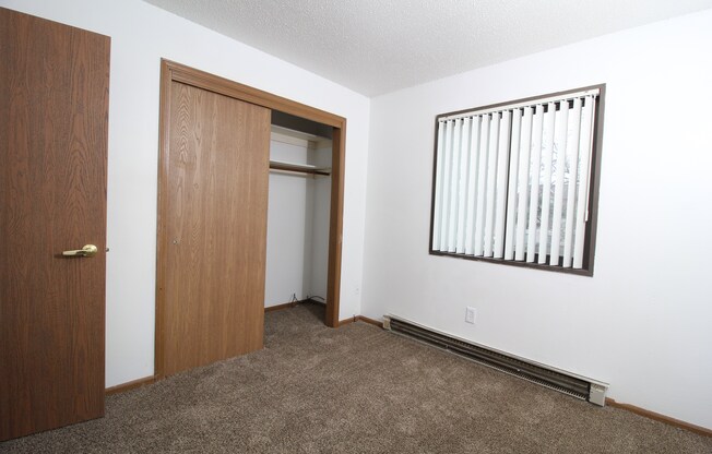 an empty room with a door open to a closet and a window